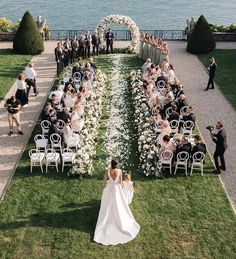 a bride and groom walking down the aisle to their wedding ceremony in front of an ocean view