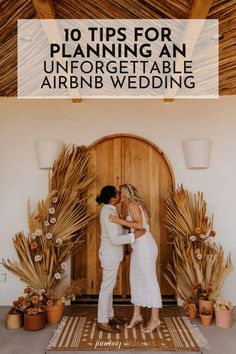 a man and woman kissing in front of a wooden door surrounded by potted plants