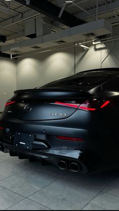 the rear end of a black car parked in a garage