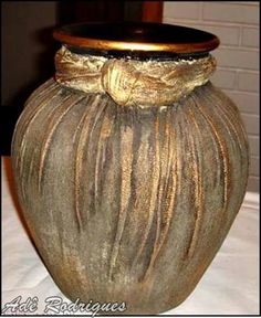 a brown vase with a gold bow on the top is sitting on a white tablecloth