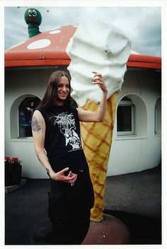 a woman standing next to an ice cream cone holding up a giant scoop of ice cream