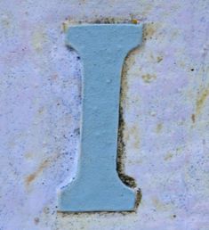 the letter i is made out of cement and has a light blue paint on it