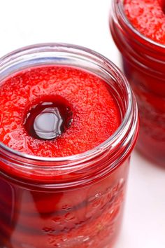 two jars filled with red liquid sitting on top of a white table next to each other