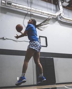 a girl is jumping in the air to dunk a basketball on an indoor court