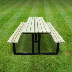 a wooden bench sitting on top of a green grass covered park field next to a lush green field