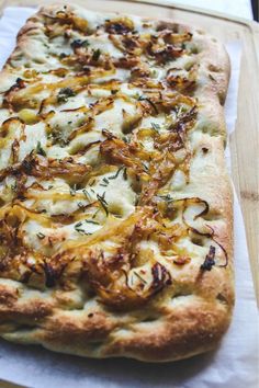 a pizza sitting on top of a wooden cutting board covered in cheese and toppings