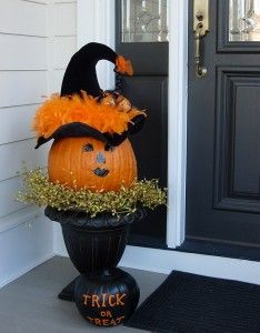 a decorated pumpkin sitting on top of a black vase in front of a door with the words trick or treat written on it