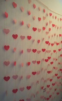 paper hearts hanging on a wall in the shape of heart's, with pink and red colors