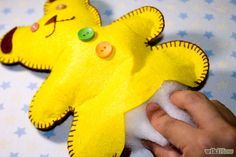 a hand is holding a yellow stuffed animal