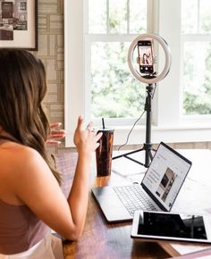 a woman sitting in front of a laptop computer on top of a table next to a camera