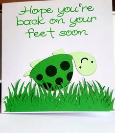 a card that says, hope you're back on your feet soon with a green dinosaur in the grass