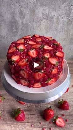 a cake with strawberries on it sitting on top of a table next to some strawberries