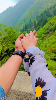 two people holding hands with mountains in the background