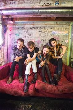 group of people sitting on top of a couch in a room with graffiti all over the walls