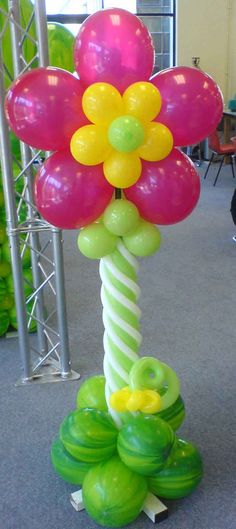 a balloon flower is on top of some green and yellow balloons in the shape of flowers