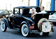 an old fashion car with a bride and groom in the back