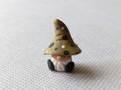 a small figurine sitting on top of a white table next to a mushroom