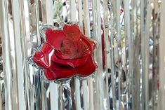 a red rose sitting on top of a piece of tin foil next to a wall