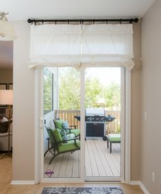 a living room with sliding glass doors leading to an outdoor kitchen and dining area in the background