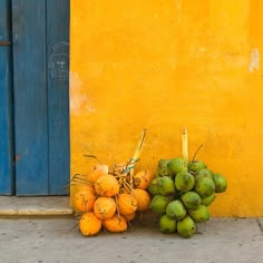 a pile of coconuts sitting next to a yellow and blue wall on the sidewalk