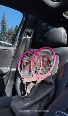 two tennis racquets sitting in the back seat of a car with pink letters on them