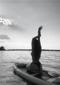 a woman sitting on top of a surfboard in the water with her arms up