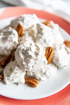 a white plate topped with ice cream and pecans on top of a pink table cloth