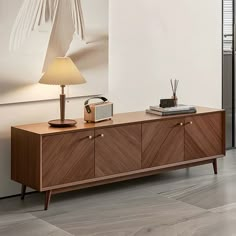 a wooden sideboard sitting on top of a hard wood floor next to a lamp