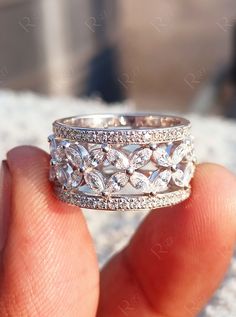 a person holding a wedding ring in their hand with diamonds on the outside and inside