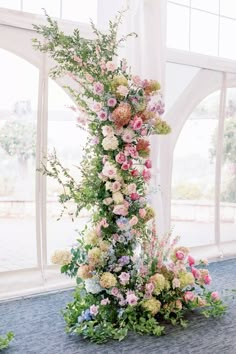 an arrangement of flowers on the ground in front of a window