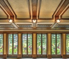 an empty room with many windows and wood trimmings on the ceiling, along with wooden flooring