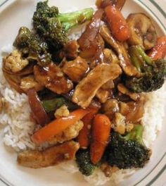 chicken, broccoli and carrots are served over rice on a white plate