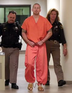 three people in orange prison jumpsuits standing next to each other