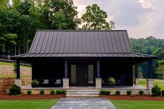 a house with a black metal roof and stone steps leading to the front door