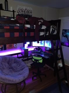 a bedroom with bunk beds, desk and computer on top of the bed is lit up by purple lights