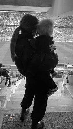 a woman holding a child in her arms at a baseball game