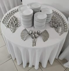 a table topped with lots of white plates and silverware