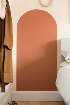 a bedroom with an arch painted on the wall next to a bed and coat rack