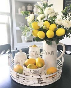 two lemons and some white roses in a vase on a table with other lemons