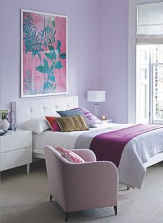 a bedroom with purple walls and two chairs in front of the bed that is up against the wall