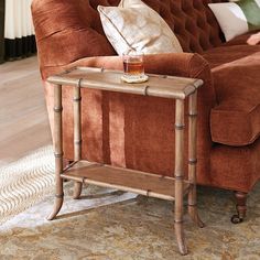 a brown couch sitting in a living room next to a table with a glass on it