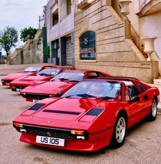 a row of red sports cars parked next to each other in front of a building