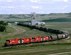 a train traveling down tracks next to a tall white building in the middle of nowhere