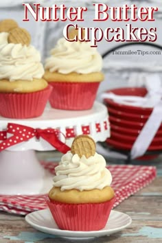 three cupcakes with white frosting and cookies on top are sitting on plates