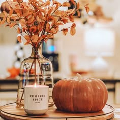 a pumpkin sitting on top of a table next to a candle