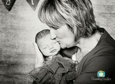 a woman holding a baby in her arms and kissing it's face on the cheek