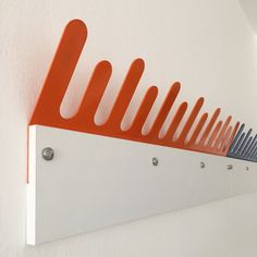 an orange and white wall mounted shelf with hooks on it's sides in a room