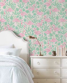 a pink flamingo wallpaper in a bedroom next to a white dresser and bed