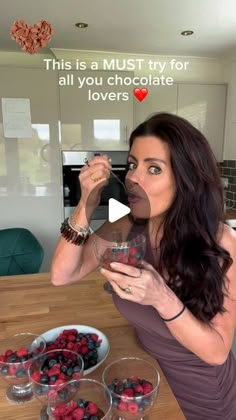 a woman drinking from a wine glass in front of some berries on the kitchen counter