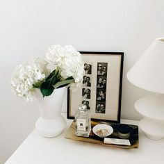 a white vase filled with flowers sitting on top of a table next to a lamp